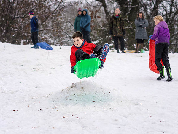 Child in mid air on a green sledge