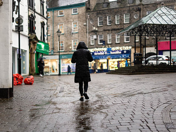 Image shows a woman walking in the rain in Kendal