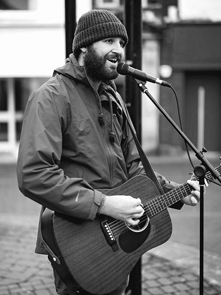 Black and white image showing a street musician in Kendal Birdcage