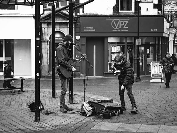 Black and white image showing a street musician in Kendal Birdcage