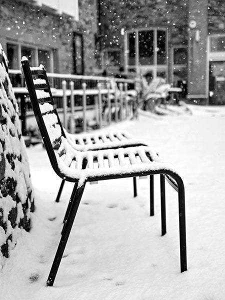 Black and white image showing chairs covered in snow