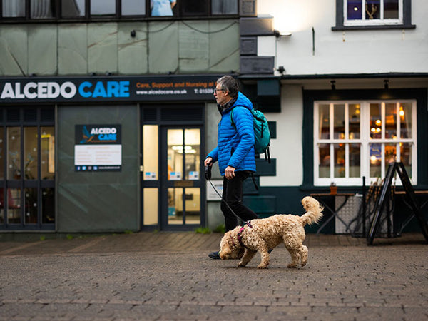 Images shows a man walking his dog