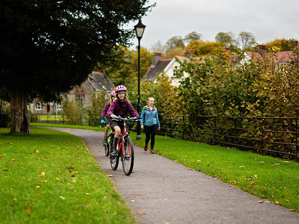 Image shows twin girls cycling along the footpath