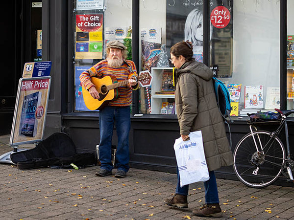 Image shows a street busker singing and playing guitar