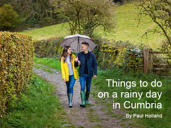 Colour image showing a young couple with an umbrella strolling down a rural lane