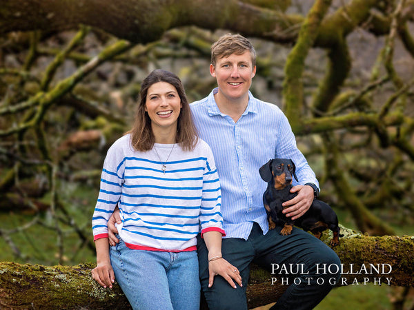 Colour image showing a man and woman outdoors with their Daschund dog