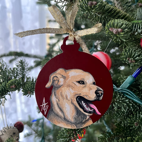 Acrylic painting of a yellow lab on a maroon background, painted on a Christmas ornament.