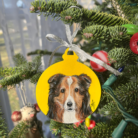 Acrylic painting of a collie dog with a yellow background on a Christmas ornament.