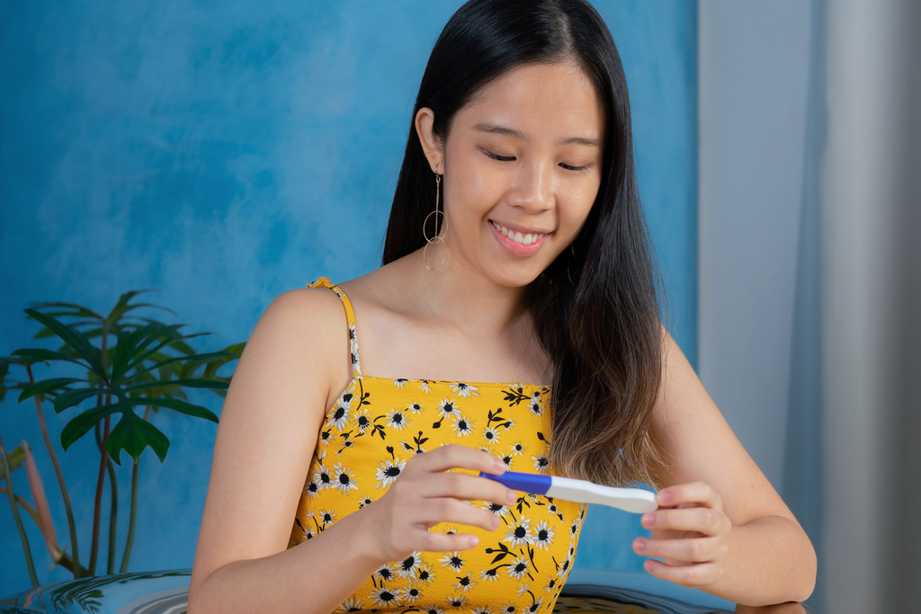 Asian woman looks at twoplus Pregnancy Test Kit happily