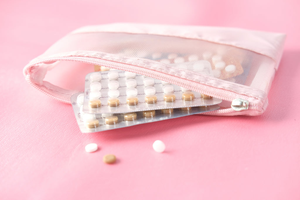 birth control pills in pink zip bag against pink background