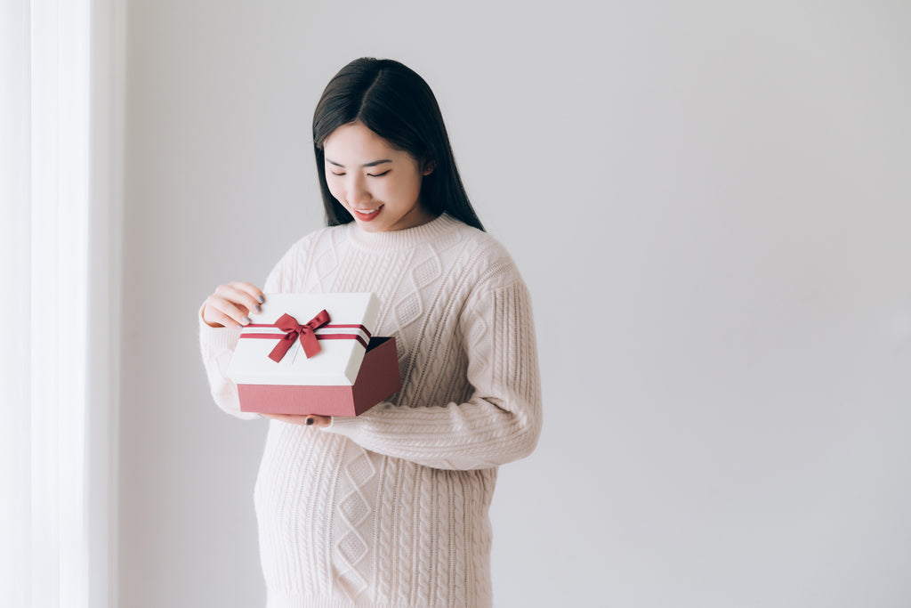 pregnant Asian woman opens gift box happily