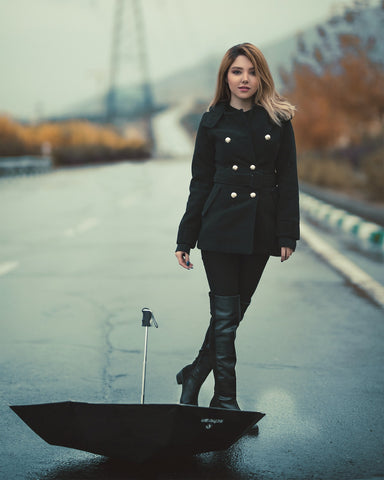 Woman wearing a double-breasted coat with black leggings and over-the-knee boots