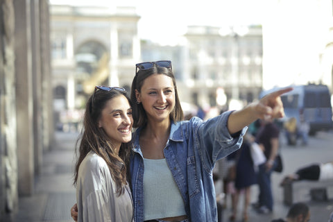 Two girls on a street smiling while wearing a  long-sleeved top and denim jacket