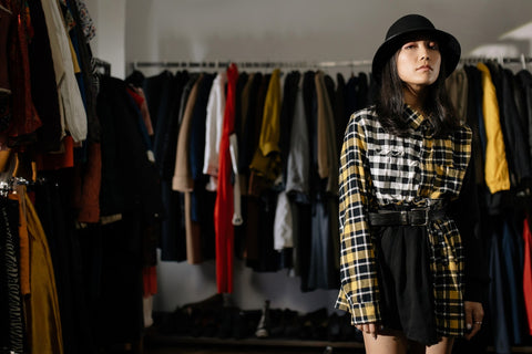 Girl wearing a  long-sleeved plaid top, black skirt, and a black hat 