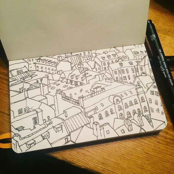 An open sketchbook showing a line drawing of copenhagen rooftops