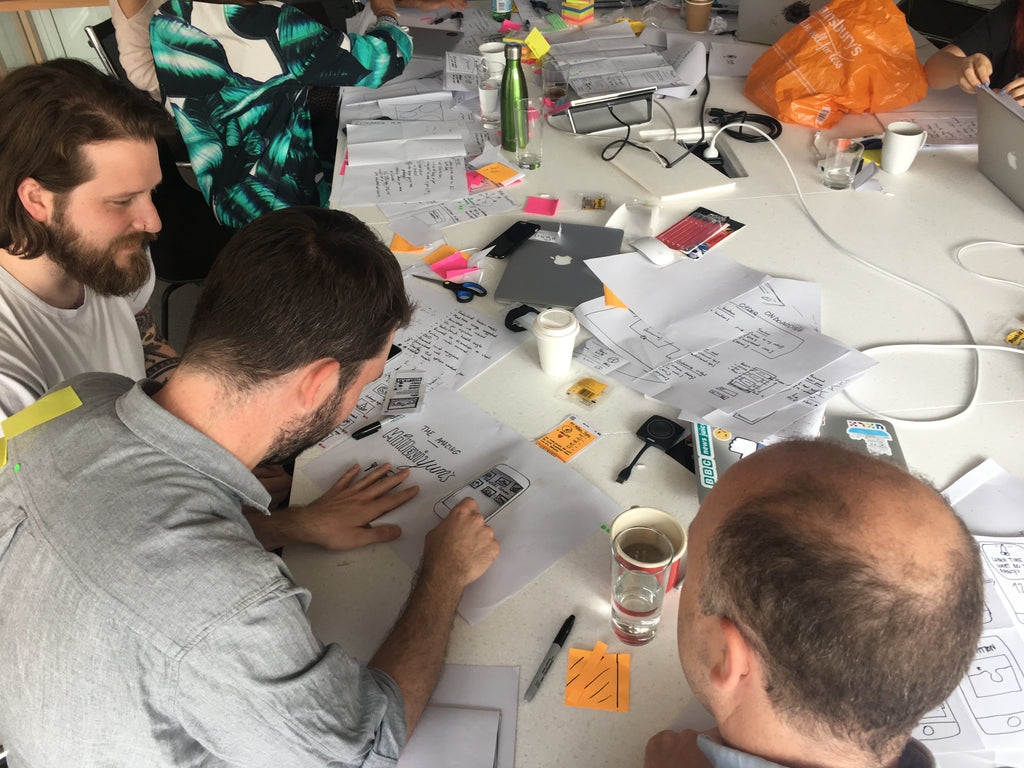 A group of people discussing paper prototypes on the table