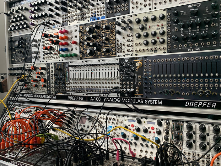 Display of an array of silver and black modules with yellow, black and red wiring by Noise Engineering 