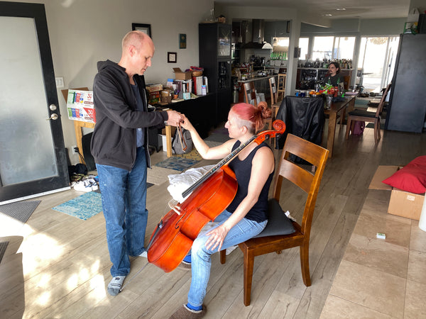 Adam showing Kris how to play cello