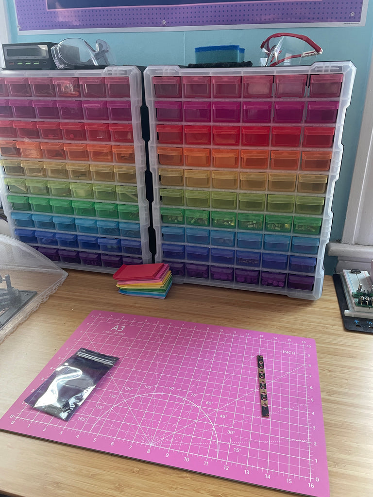 Rainbow-colored drawers on a desk with a pink cutting mat