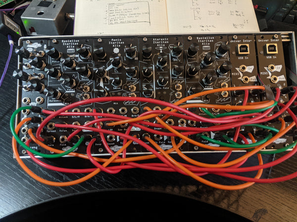A 60 HP eurorack case with four Alia voices, two Univer Inter, and a Xer Dualis mixer, patched densely for a four-voice polyphonic patch