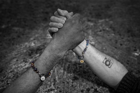 2 men arm-wrestling with beautiful beaded bracelets