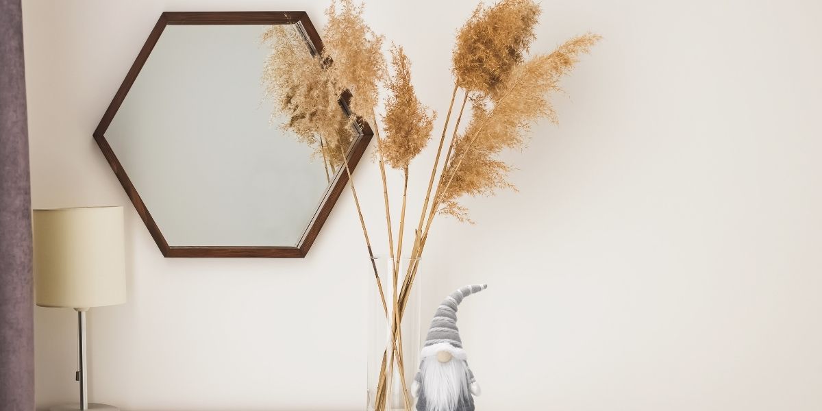 Nordic Minimalist style dressing table with mirror hanging and pampas grass in glass vase. Grey Christmas gonk beside the pampas grass