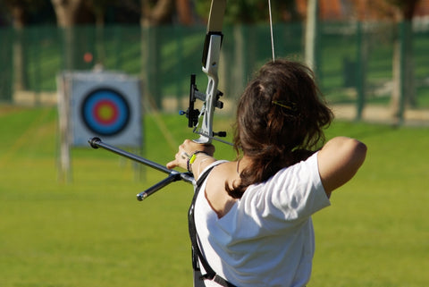 An archery athlete aiming at a target in the distance