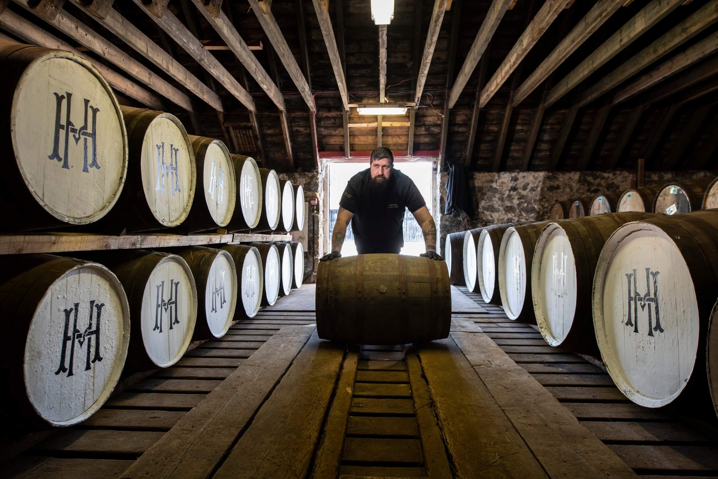 The whisky maker rolling a barrel into a storage cellar.