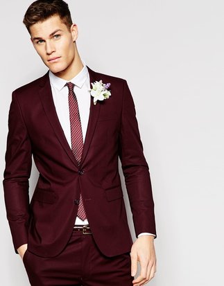 Man wearing a maroon suit for his wedding with a matching tie and flower boutonniere