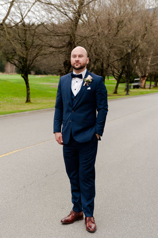 Man in a navy suit with a matching bow-tie and a white pocket square