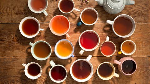 A flat lay of multiple mugs of steeped tea. 
