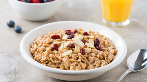 Beautiful food photography: a warm bowl of tea-steeped oatmeal topped with dried cranberries and slivered almonds. Recipe made using Tetley Warmth tea. 