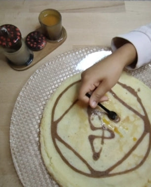 Logo d'e-fantina.com dessiné sur une crêpe. Tartiné de compotée d'abricots servie dans un duo de saucières sur socle en palissandre.