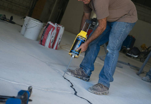 A person filling a concrete crack with epoxy