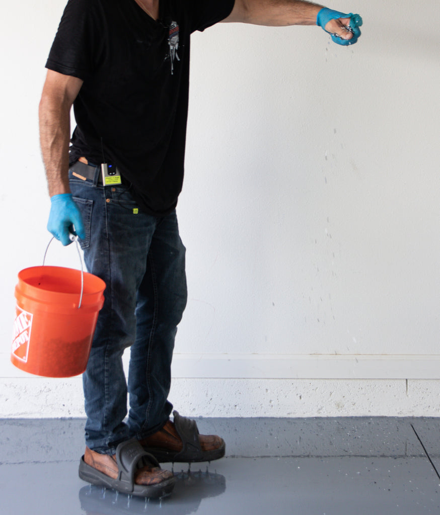 An image of an epoxy resin flooring contractor broadcasting vinyl flake onto an epoxy resin floor.