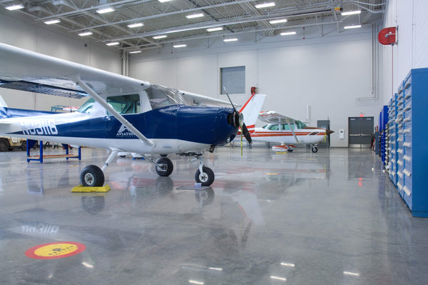 An image of a commercial airport hangar with two airplanes parked on a polished concrete floor.