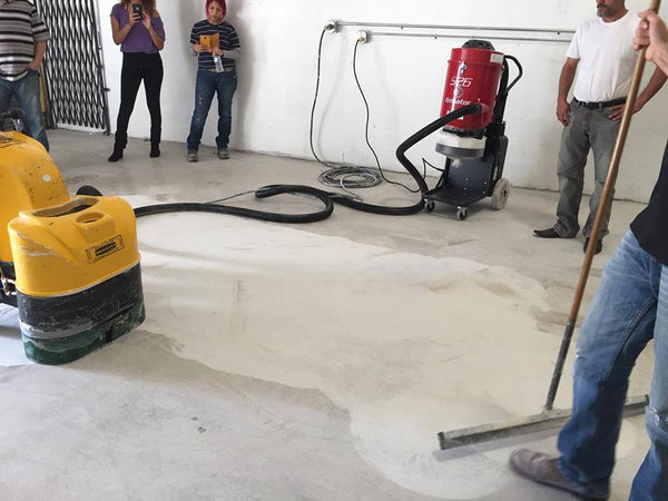 An image of Xtreme Polishing Systems Concrete Genie Floor Grinder which is hooked up to an Ermator Dust Extractor and is grinding a concrete floor surface.