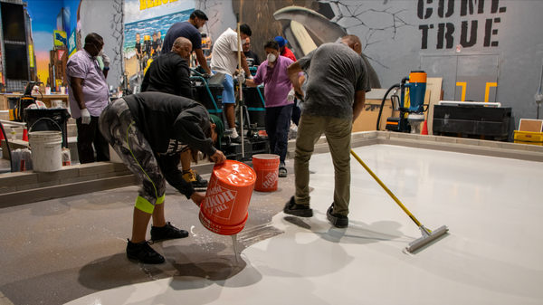 Multiple installers applying a self-leveling concrete product to a floor.