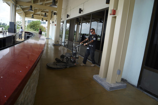 An image of a male installer using a floor burnisher on a concrete floor balcony inside a casino.