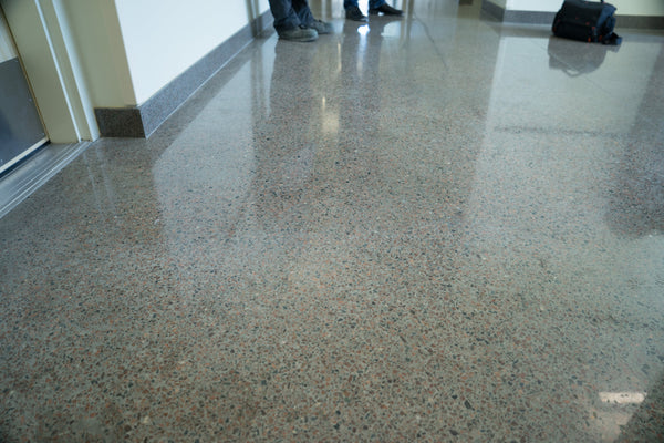 An image of a highly reflective polished terrazzo floor with people standing in the background.