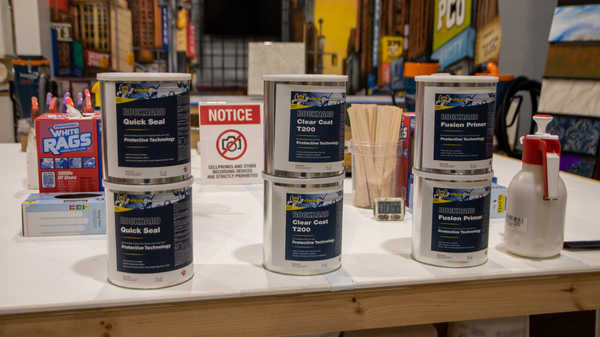 An image of a table with Rockhard cans of ClearCoat Sealer, T200 Protectant, and Fusion Primer.