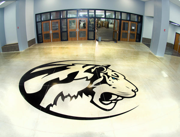 A concrete floor inside a school with a mascot logo on the floor.