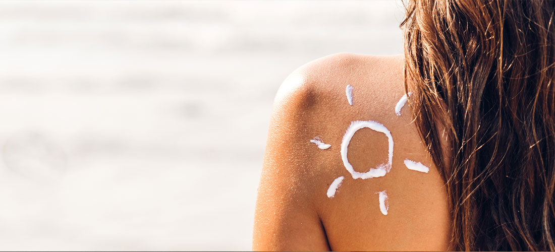 A creative image displaying a woman's shoulder with a playful sun drawing meticulously crafted using sunscreen, symbolizing the importance of sun protection in a fun and artistic way.