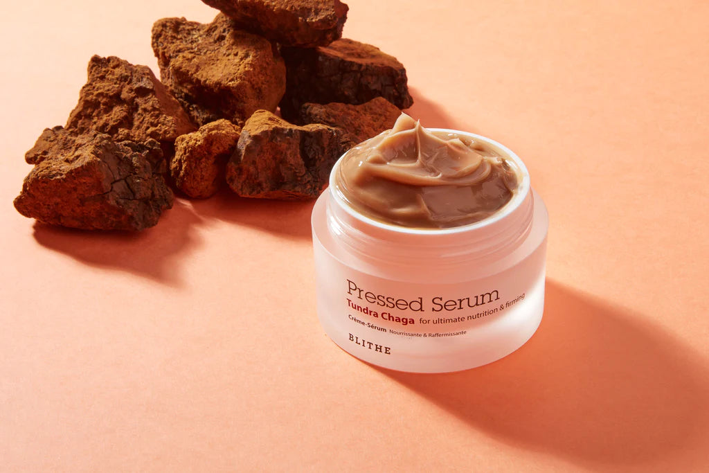 a container of Blithe Cosmetics’ Pressed Serum beside brown chaga mushrooms