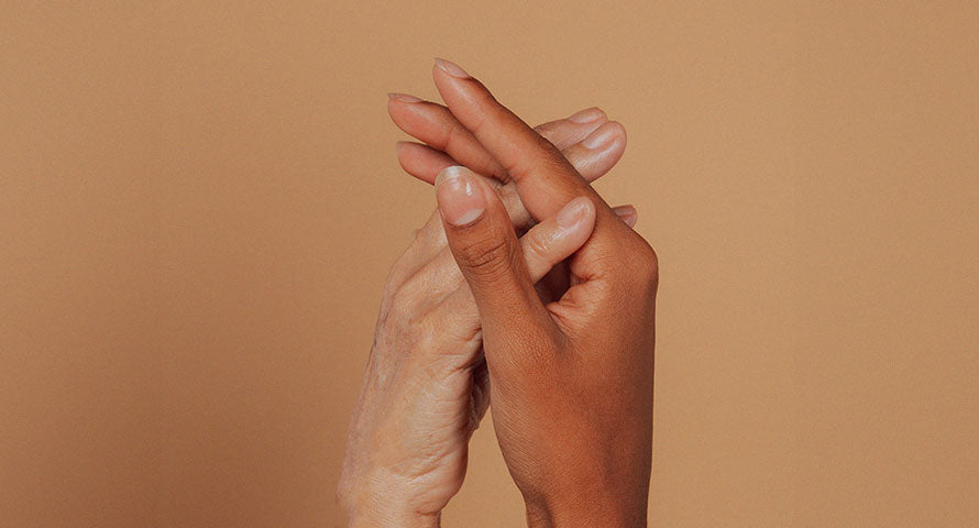 A close-up image of two hands clasped together, one belonging to an older woman and the other to a younger woman, showcasing the bond between generations and the importance of passing down skincare knowledge and practices.