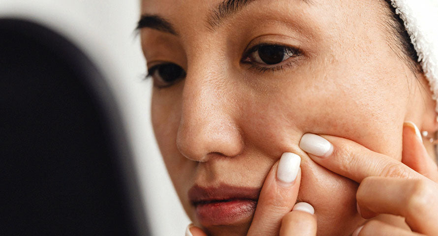 A woman gazing into a mirror, reflecting a moment of self-care and introspection as part of her skincare routine.