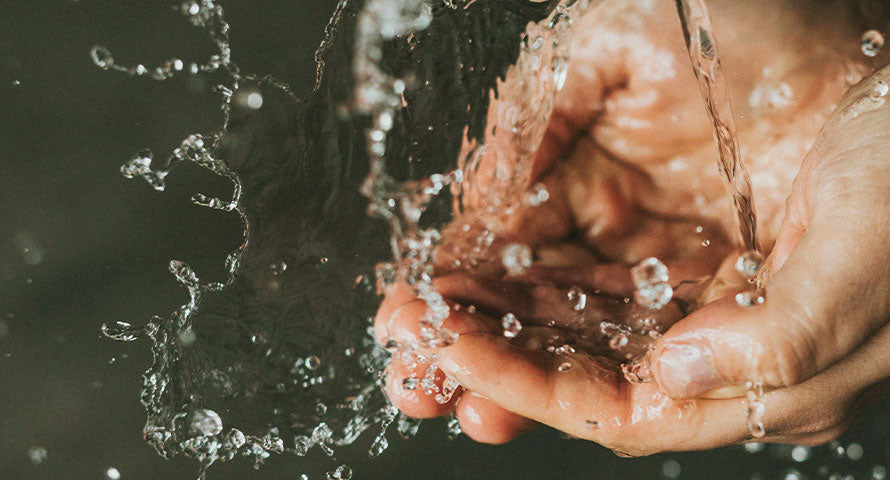 Image of hands splashing clear water, symbolizing the refreshing and vital role of hydration in skin health and barrier maintenance.