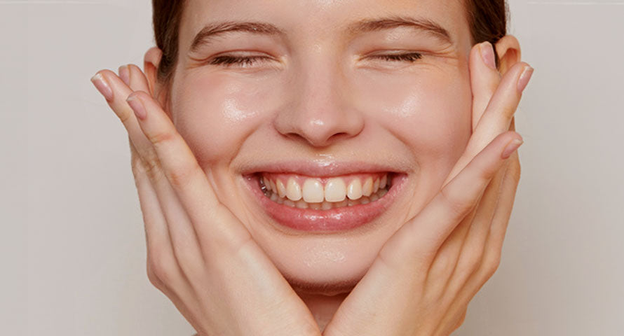 Close-up image of a woman smiling warmly at the camera, her face radiating confidence and happiness, highlighting healthy, glowing skin.