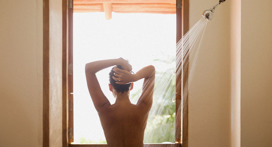 A woman standing under a showerhead, feeling the refreshing flow of water, highlighting the rejuvenating experience of daily showers.