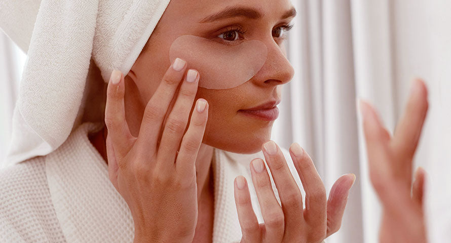 A woman applying an eye gel patch, focusing on skincare and self-care to rejuvenate the delicate skin around her eyes.